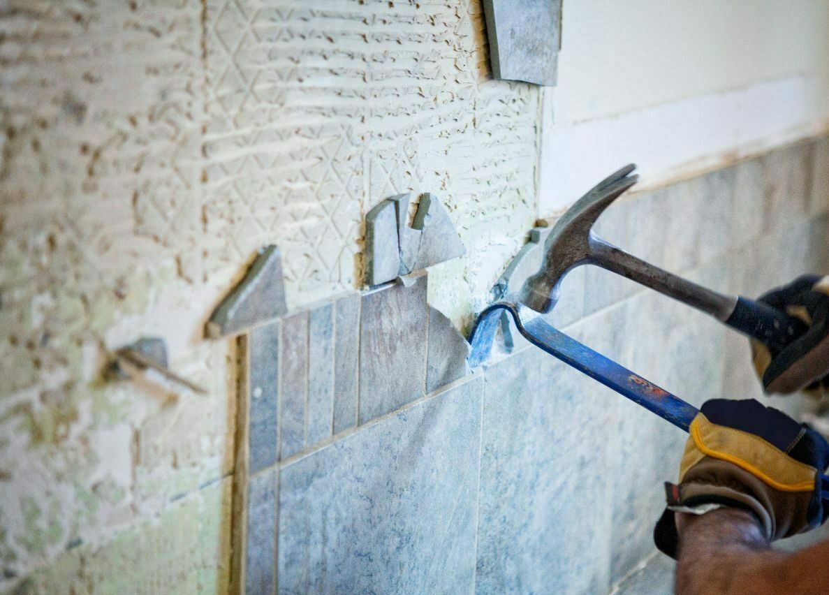 a handyman is doing wall renovations on a property for sale in bali using a hammer